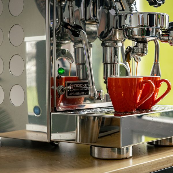 Professionelle Espressomaschine brüht Kaffee in rote Tasse auf Holztheke in moderner Küche