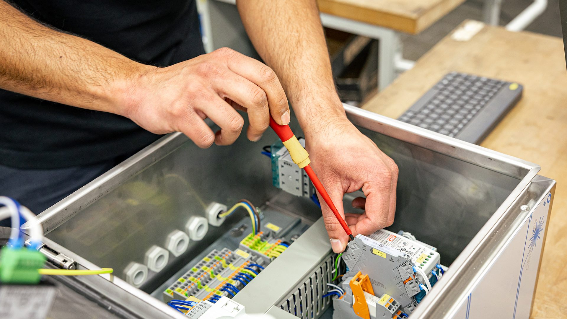 Techniker arbeitet mit rotem Werkzeug an elektronischen Komponenten in einem geöffneten Antriebssystem-Gehäuse