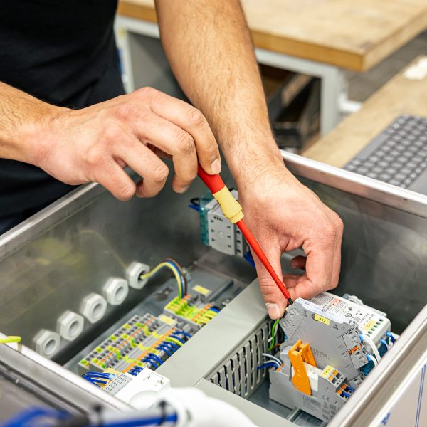 Techniker arbeitet mit rotem Werkzeug an elektronischen Komponenten in einem geöffneten Antriebssystem-Gehäuse