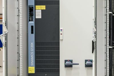 Industrielle Schaltanlage mit SINAMICS G120X Frequenzumrichter und Bedienfeld in grauem Schaltschrank
