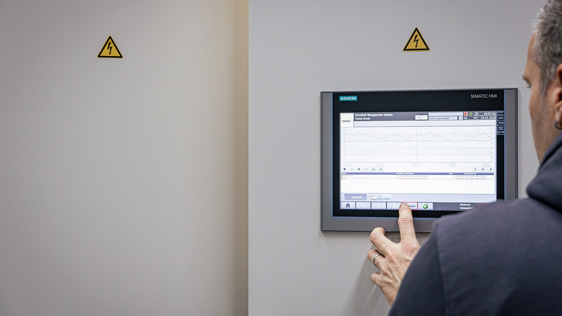 Mann bedient Siemens Touchscreen-Panel zur Steuerung eines Druckluft-Management-Systems