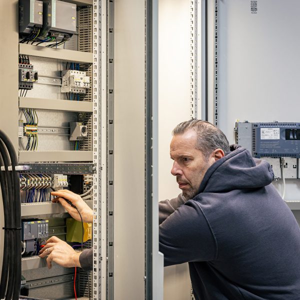 Techniker arbeitet an offener Schaltanlage zur Wartung eines Druckluft-Management-Systems