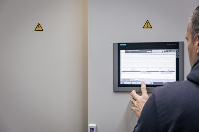 Mann bedient Siemens Touchscreen-Panel zur Steuerung eines Druckluft-Management-Systems