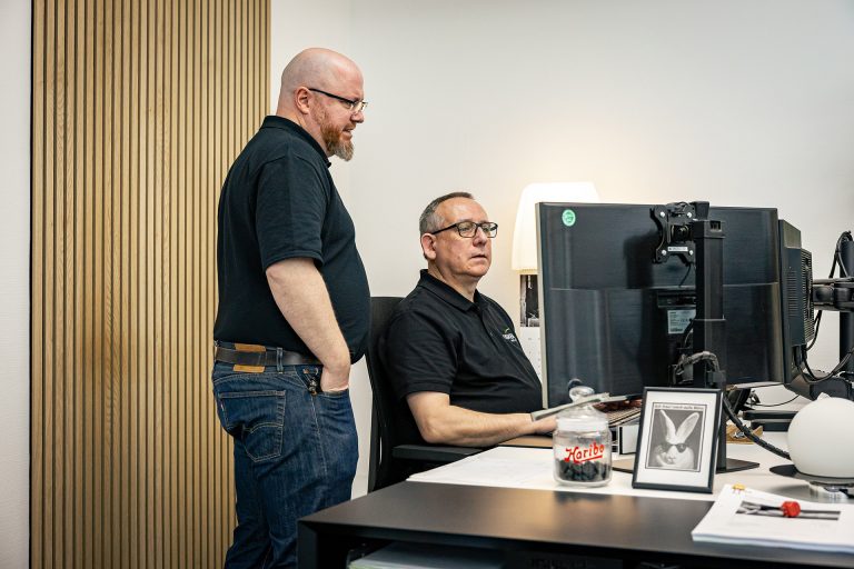 Zwei Techniker arbeiten gemeinsam am Computer für Fernwartung und IT-Service in modernem Büro