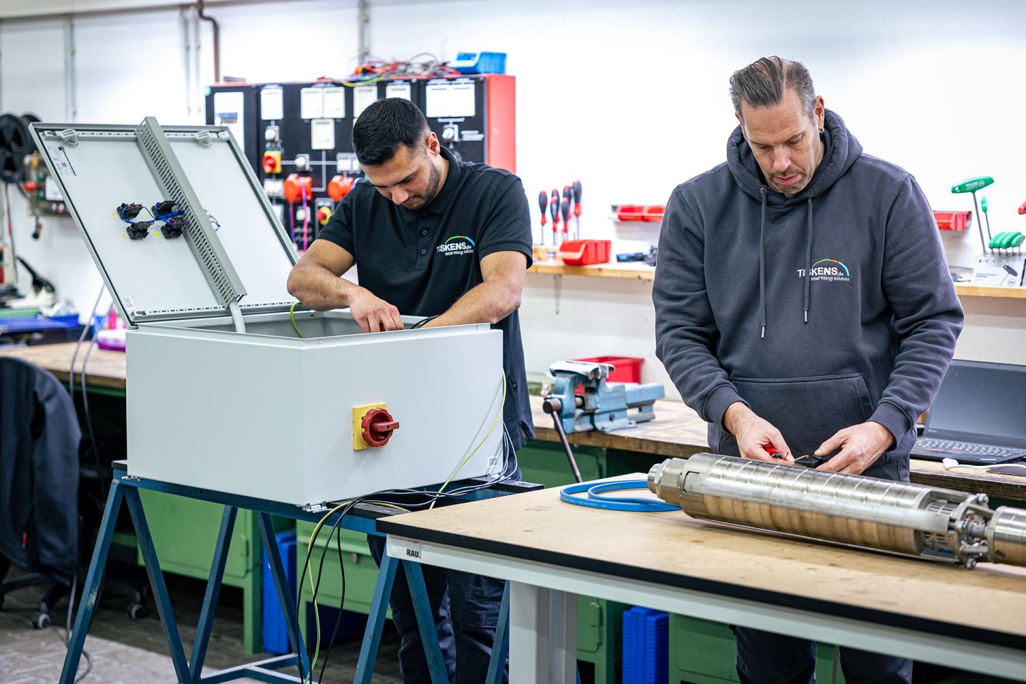 Zwei Techniker warten eine Pumpe in der Werkstatt - einer bedient Prüfgerät, der andere montiert Pumpenkomponenten