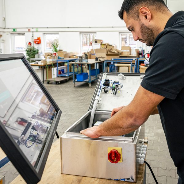 Techniker arbeitet an Retrofit-Maschine mit Touchscreen-Monitor in Industriewerkstatt