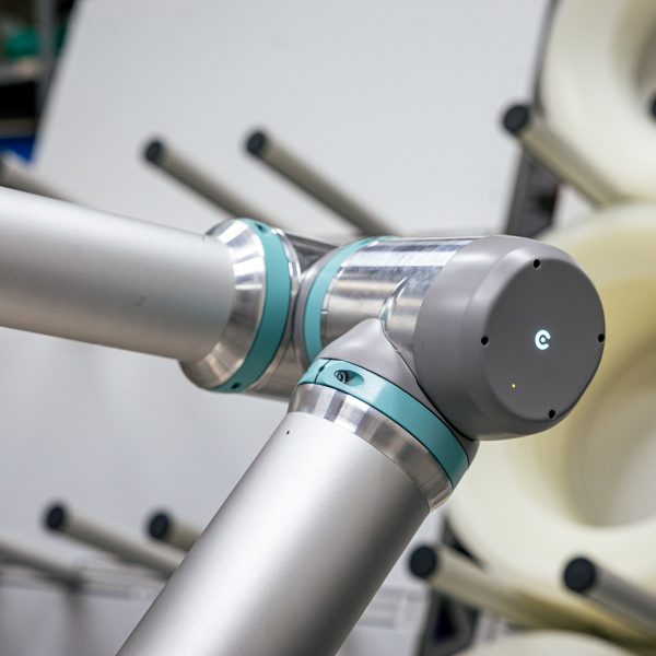 Roboterarm-Gelenk mit türkisen Dichtungen und silbernen Komponenten in industrieller Umgebung